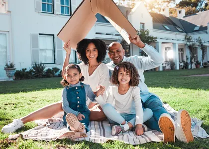 A family sitting together on the lawn outside their home